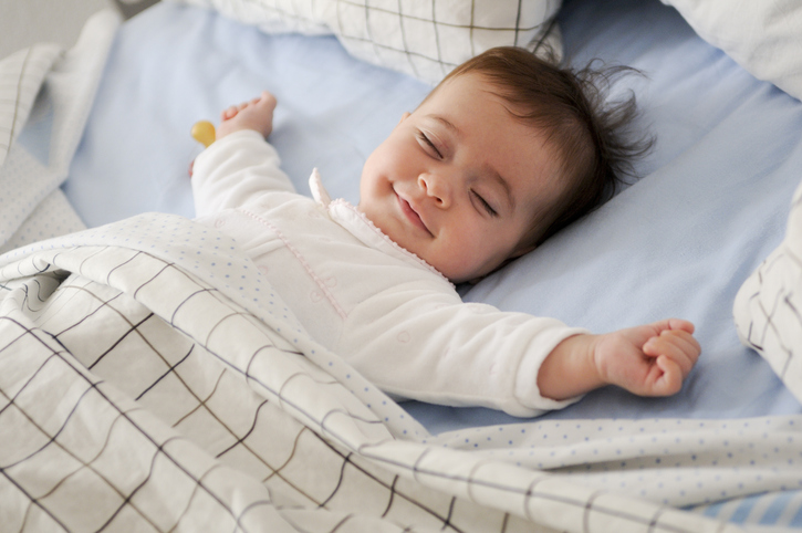 Smiling baby girl lying on a bed Slapende baby van 4 maanden